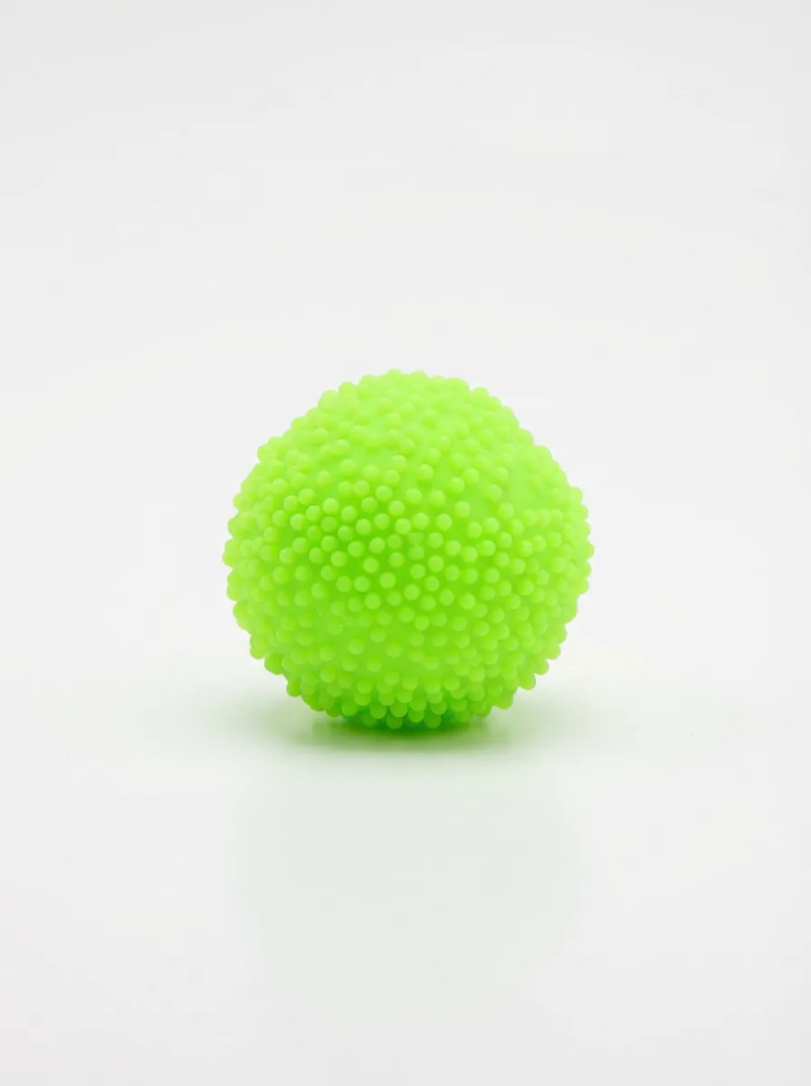 A vibrant neon green NeeDoh Gumdrop stress ball sitting alone on a white surface, casting a soft shadow.